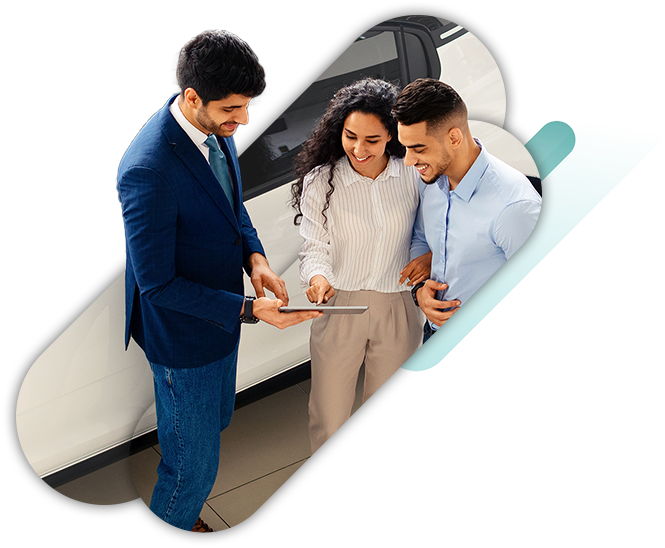 Auto dealer working with a young couple reviewing financing options on a tablet in the showroom