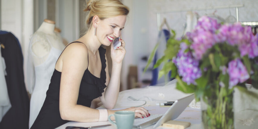 Woman on the phone with a laptop looking up wedding financing options