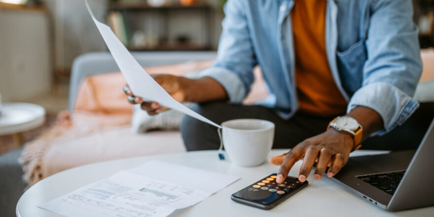 A man at home calculating APR and interest rate on a phone calculator