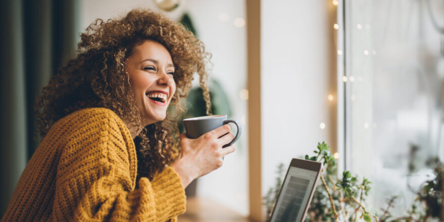 A woman laughing and having coffee - Upstart Personal Loans