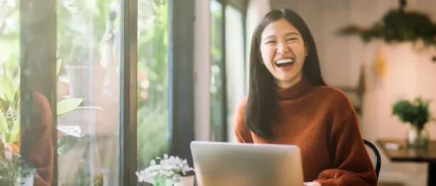 Woman laughing in front of her computer - Upstart Personal Loans