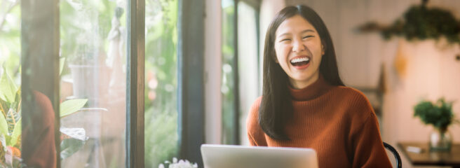 Woman laughing in front of her computer - Upstart Personal Loans