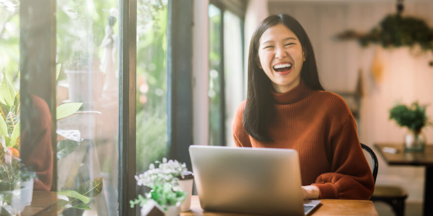 Woman laughing in front of her computer - Upstart Personal Loans