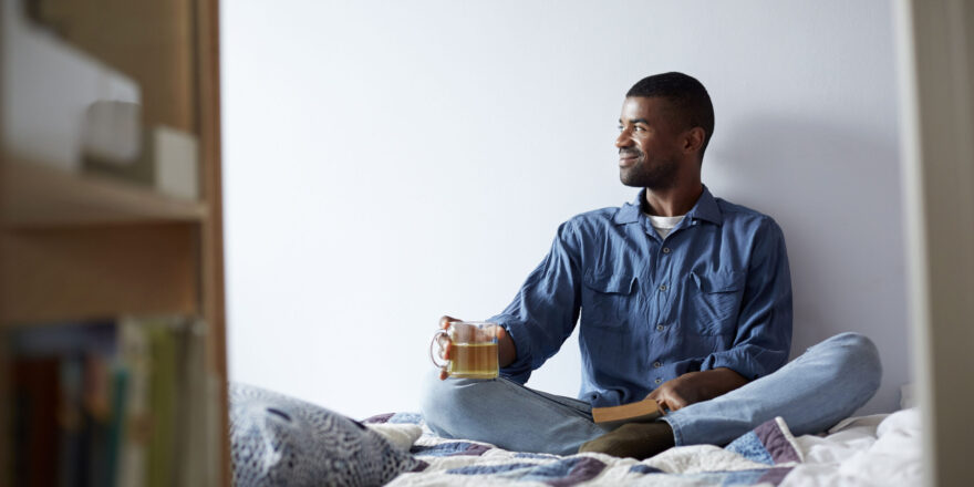 Man practicing self care with tea and a book