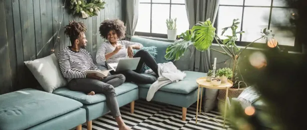 Two people sitting on a couch smiling - Upstart Personal Loans
