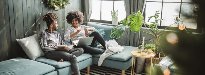 Two people sitting on a couch smiling - Upstart Personal Loans