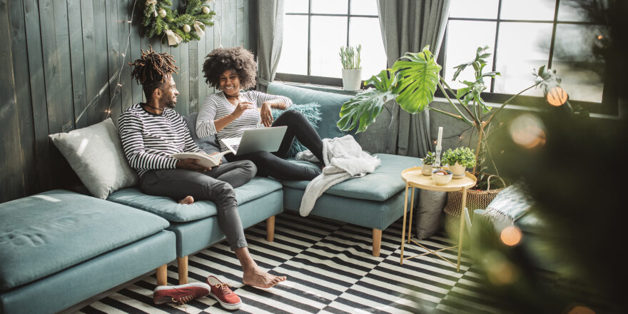 Two people sitting on a couch smiling - Upstart Personal Loans