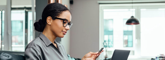 Young woman making online payment while sitting in the living room on sofa