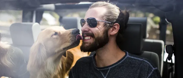 Man in a car getting licked by his dog - Upstart Personal Loans