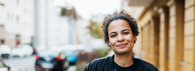 A portrait of a stylish young woman smiling on the way to meet some friends.