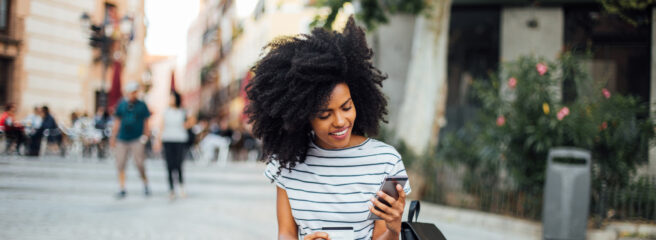 Woman sitting on steps researching personal loans on a mobile phone.