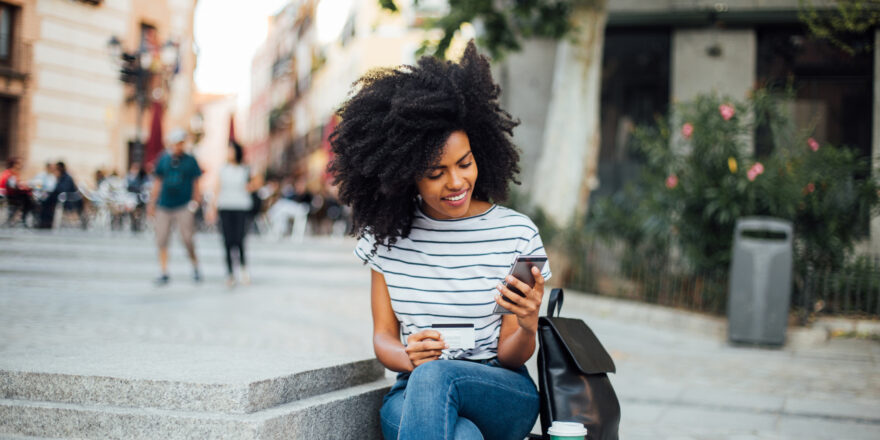 Woman sitting on steps researching personal loans on a mobile phone.