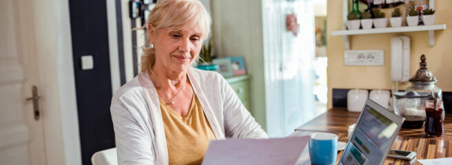 Senior woman in front of computer comparing unsecured and secured personal loans with paperwork in hand.