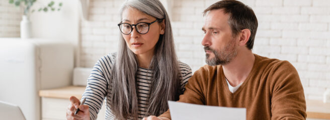 Woman and man sitting at a desk in an office looking at a laptop doing research for best personal loans.