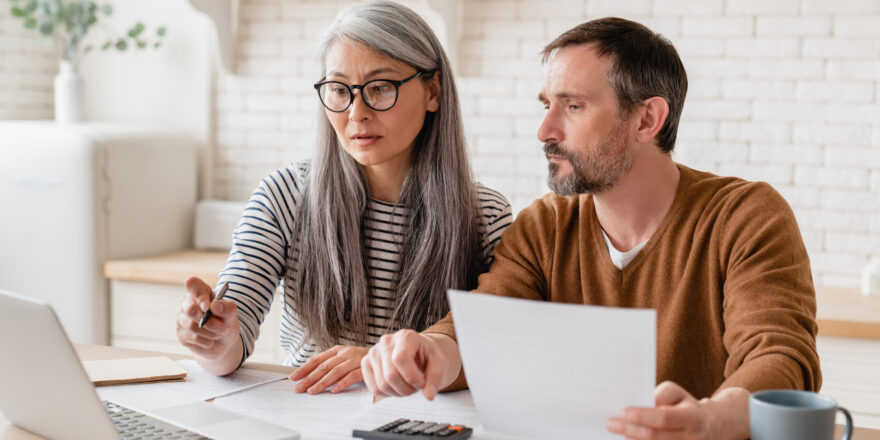 Woman and man sitting at a desk in an office looking at a laptop doing research for best personal loans.