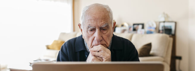 Man sitting in the living room and looking at his laptop while looking for a good personal line of credit option