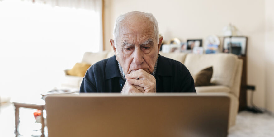 Man sitting in the living room and looking at his laptop while looking for a good personal line of credit option