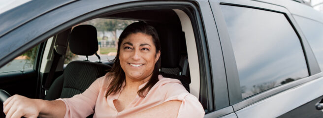 Woman in pink shirt sitting in car with the window down