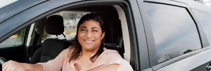 Woman in pink shirt sitting in car with the window down