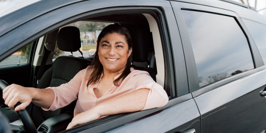 Woman in pink shirt sitting in car with the window down