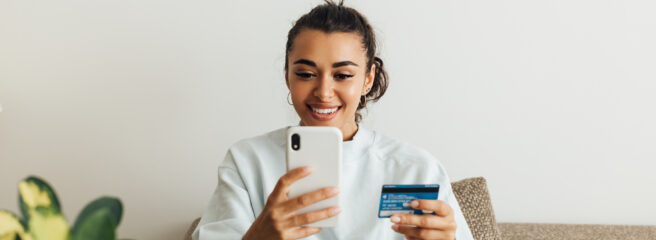 Woman sitting on her couch using her cellphone to search for details on credit card refinancing.