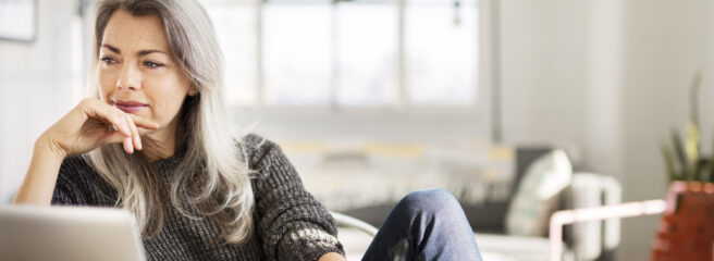 Woman sitting at her desk taking notes on personal loans to pay off credit cards.