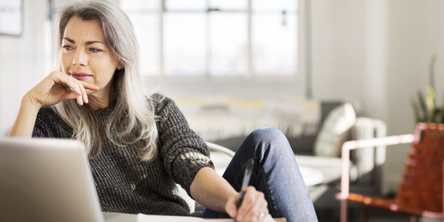 Woman sitting at her desk taking notes on personal loans to pay off credit cards.