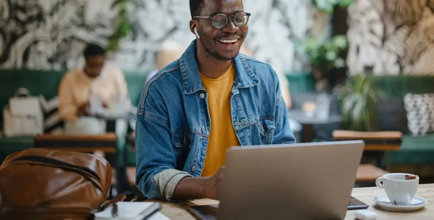 Man working at cafe on laptop and smiling