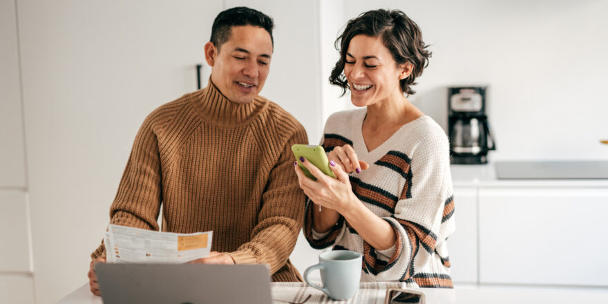 Couple sits at kitchen counter and reviews different types of loans while drinking coffee