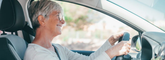 Woman sits behind the wheel of her car while considering ways to get a lower car payment