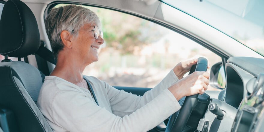 Woman sits behind the wheel of her car while considering ways to get a lower car payment