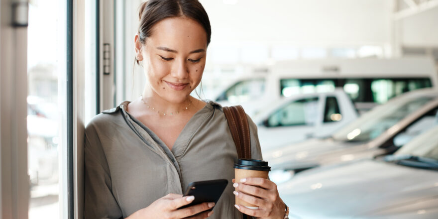 Woman holds a cup of coffee while considering the pros and cons of buying out a car lease