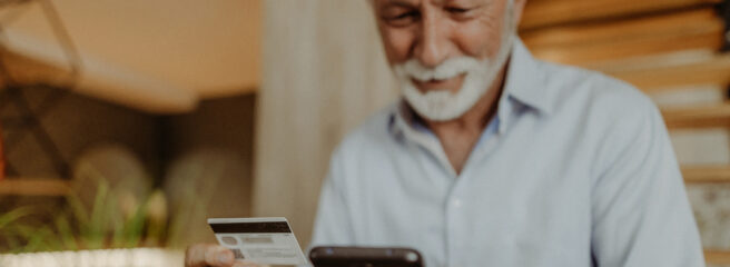 A man uses his cellphone and credit card to make a purchase online