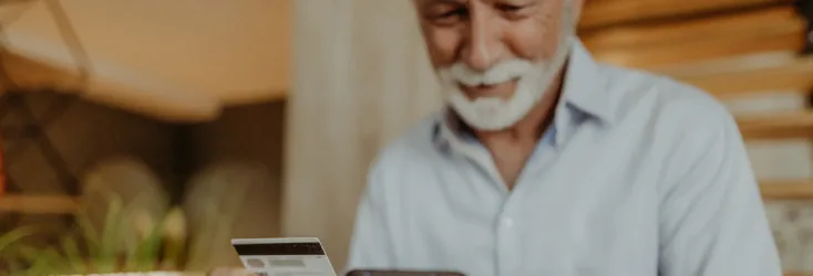 A man uses his cellphone and credit card to make a purchase online