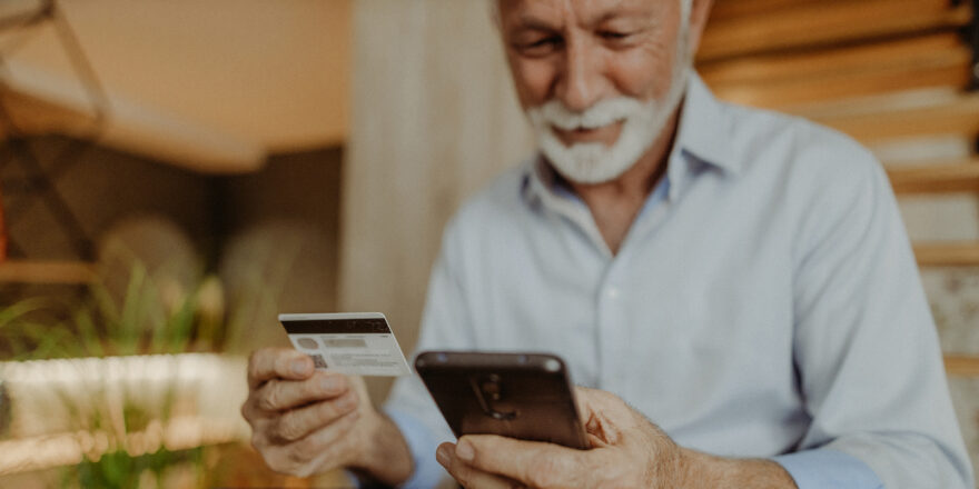 A man uses his cellphone and credit card to make a purchase online