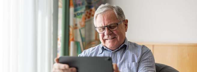 An elderly man researches at home on his iPad what to do before a credit check to get approved.