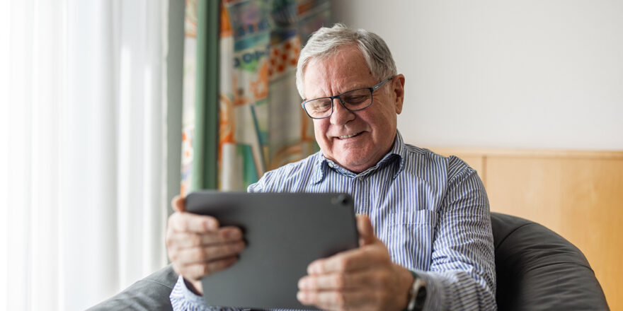 An elderly man researches at home on his iPad what to do before a credit check to get approved.
