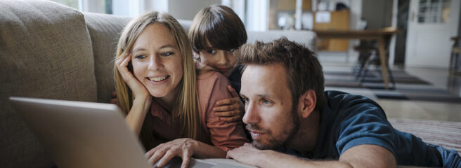 A family uses a laptop while sitting together on the couch