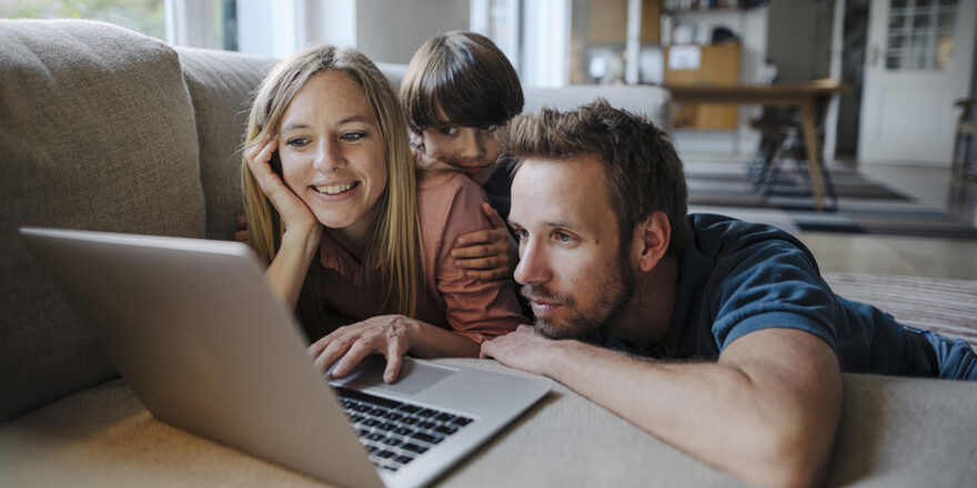 A family uses a laptop while sitting together on the couch