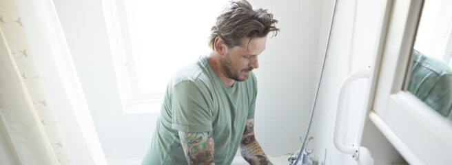 A man uses tools to work on a bathroom remodel in a house.