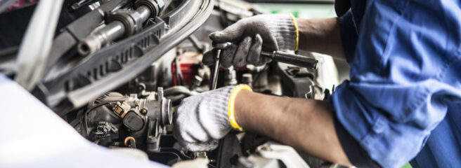 A mechanic works on a car engine in a repair shop