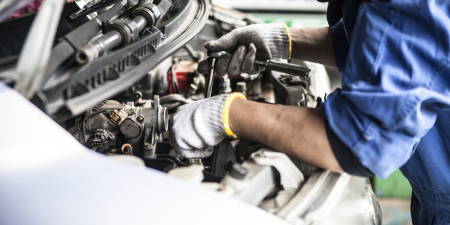 A mechanic works on a car engine in a repair shop