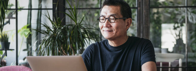 Older man in glasses looking up small business loans on a laptop