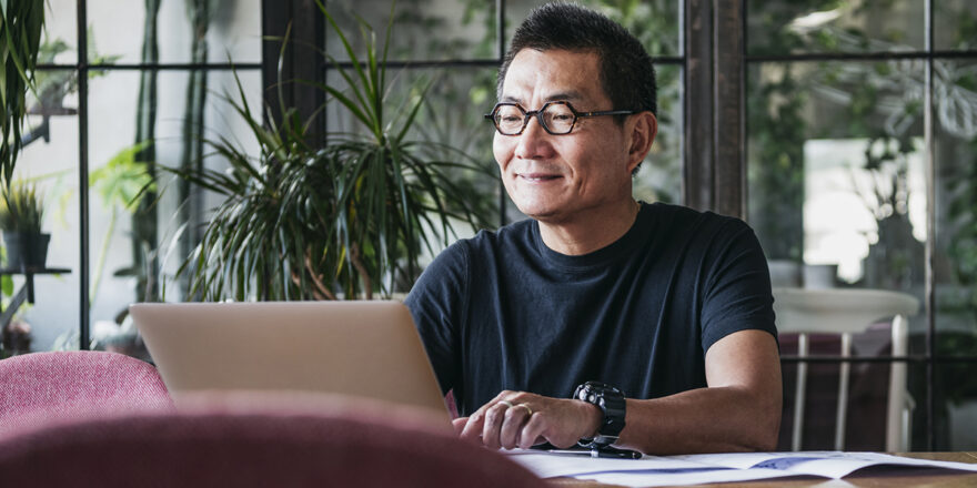 Older man in glasses looking up small business loans on a laptop