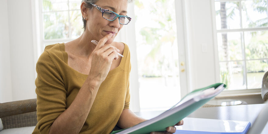 An older woman studies at home what a principal payment is and discovers if it will help save money on her loan.