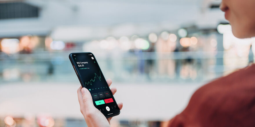 A person uses their cell phone to view the stock market and changes resulting from a bear market.