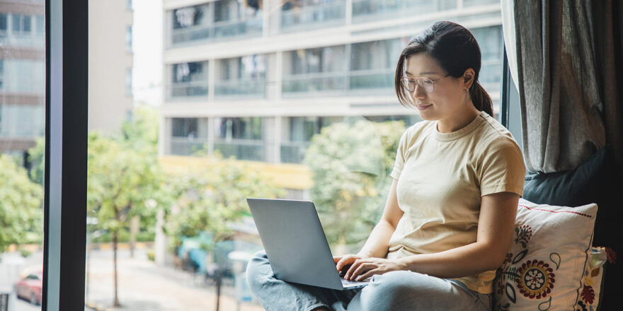 A woman uses a laptop to research stagflation and how to prepare for it financially