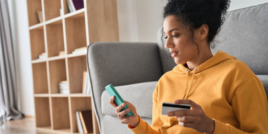 Young woman holding a phone in one hand and a credit card in another hand