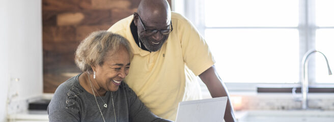 Senior couple in the kitchen looking at laptop about refinancing and credit
