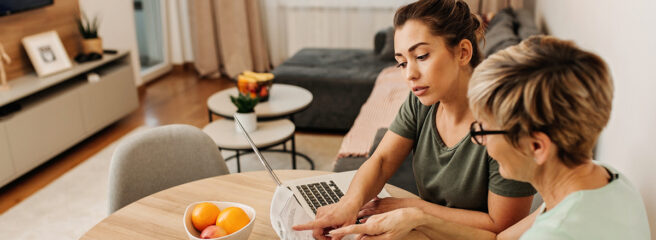 Mother and daughter discussing personal loan origination fee with a laptop